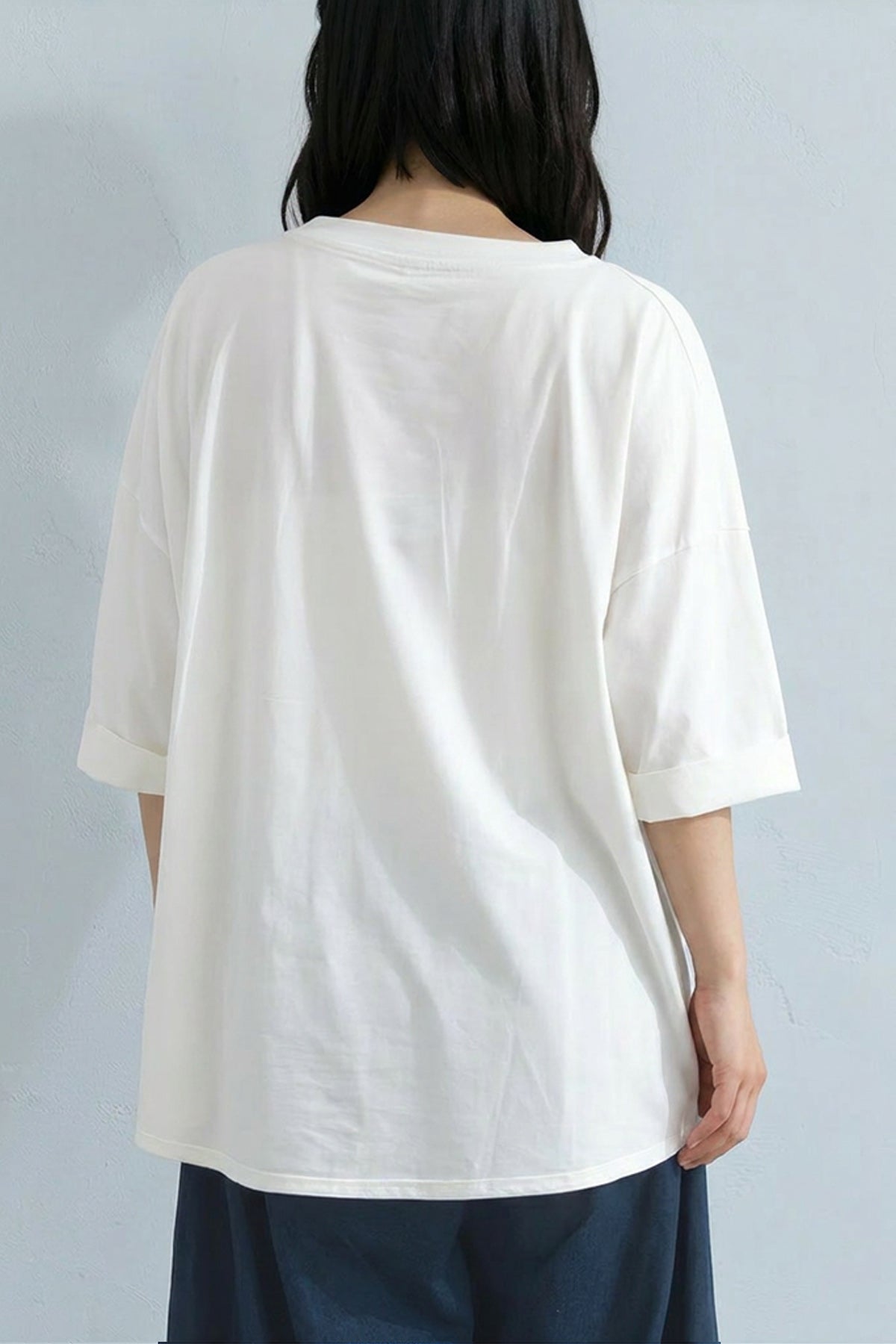 Person wearing a white oversized shirt against a plain background